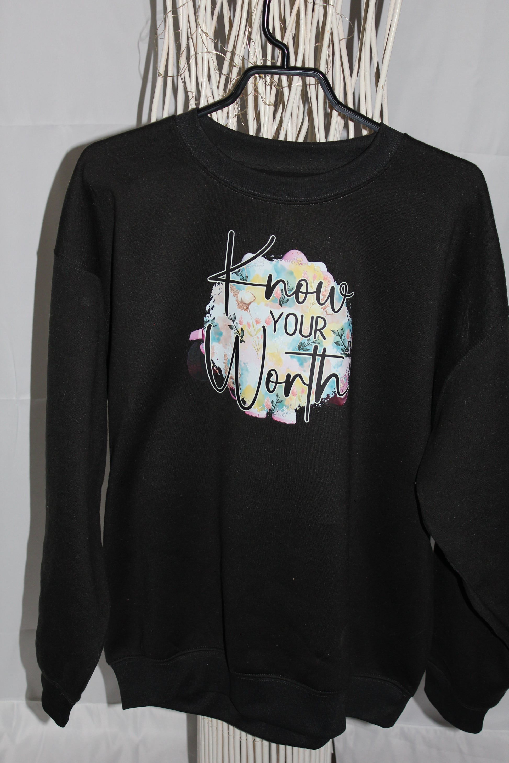 Crewneck femme noir col rond avec message “Know Your Worth” et fond floral pastel